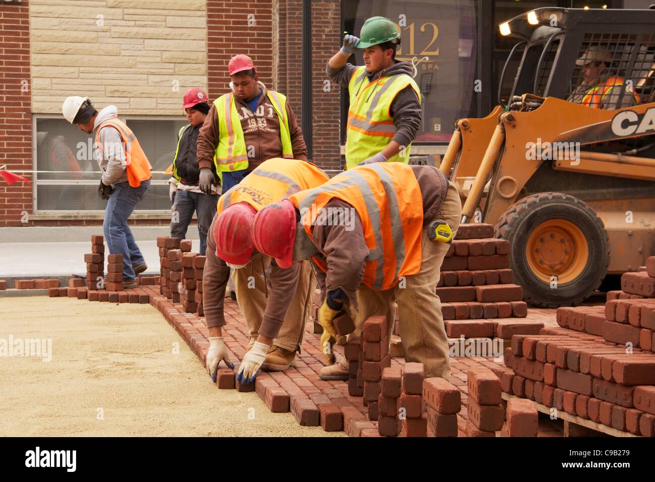 Les travailleurs de la construction poser pavés au cours du projet de reconstruction de la rue Marion le samedi 19 novembre 2011 à Oak Park, Illinois, États-Unis. La brique est utilisée pour retourner la rue dans son aspect du début du xxe siècle et de réduire le ruissellement. Banque D'Images