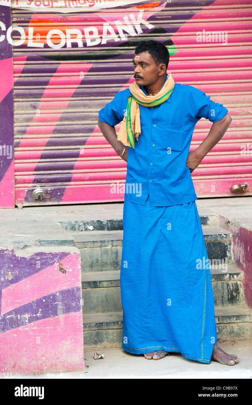 L'Inde, de l'homme pèlerin religieux hindous habillé de bleu debout à côté d'colorbank signe. Puttaparthi, Andhra Pradesh, Inde Banque D'Images