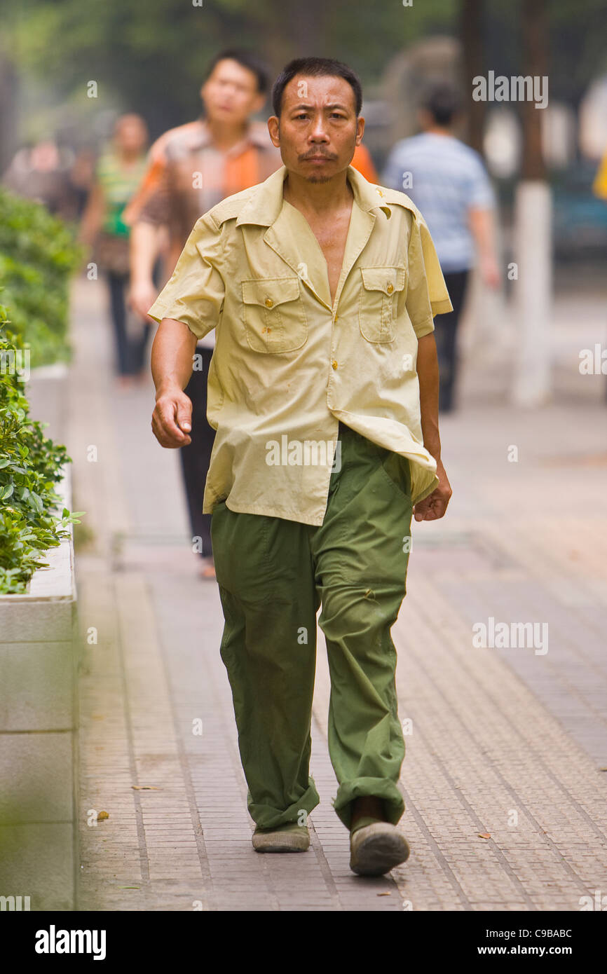 GUANGZHOU, province de Guangdong, Chine - homme marchant sur un trottoir, dans la ville de Guangzhou. Banque D'Images