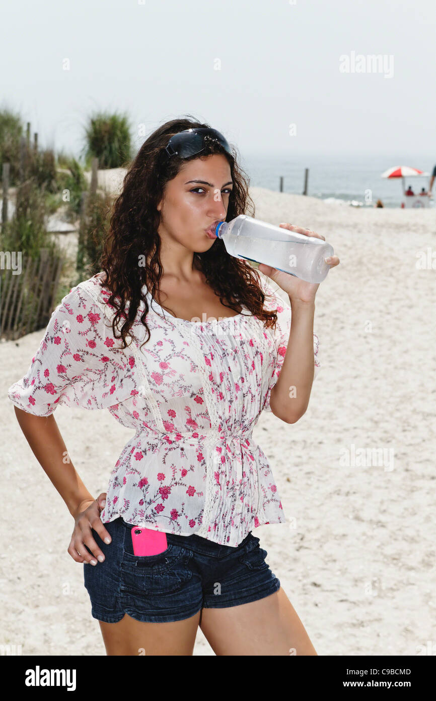 Jeune femme à boire de l'eau en bouteille sur la plage, Atlantic City, New Jersey Banque D'Images