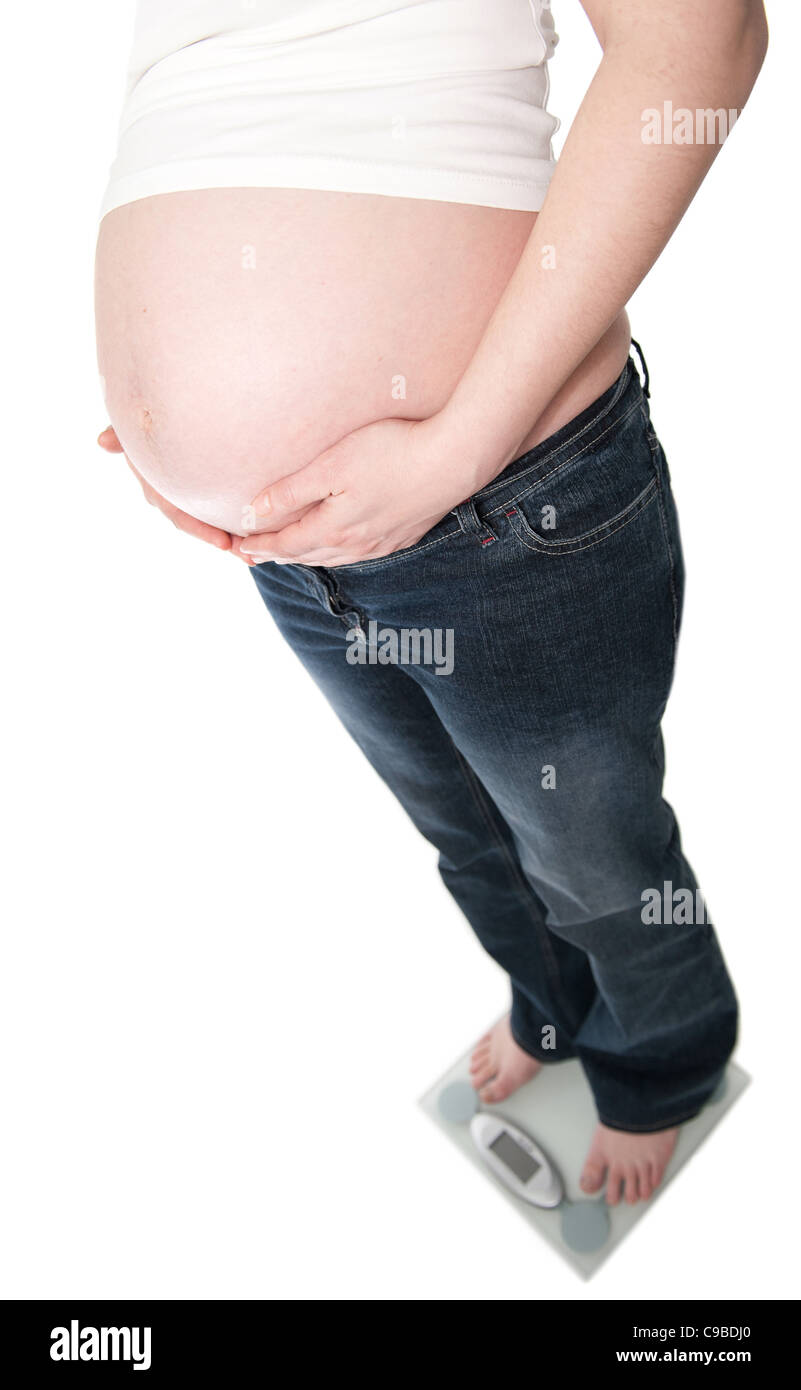 Femme enceinte, debout sur l'échelle de poids, isolé sur fond blanc Banque D'Images