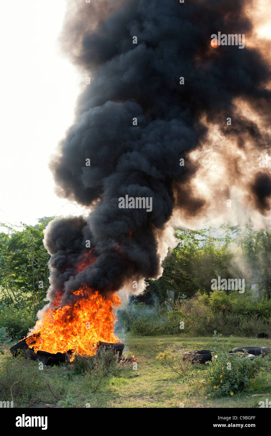 Pneumatiques gravure dans la campagne indienne de polluer l'air avec une épaisse fumée noire. L'Andhra Pradesh, Inde Banque D'Images