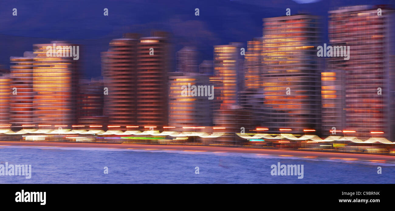 Profil de l'architecture floue la plage Levante de Benidorm au coucher du soleil, avec le soleil qui reflète sur windows et les bâtiments. Banque D'Images