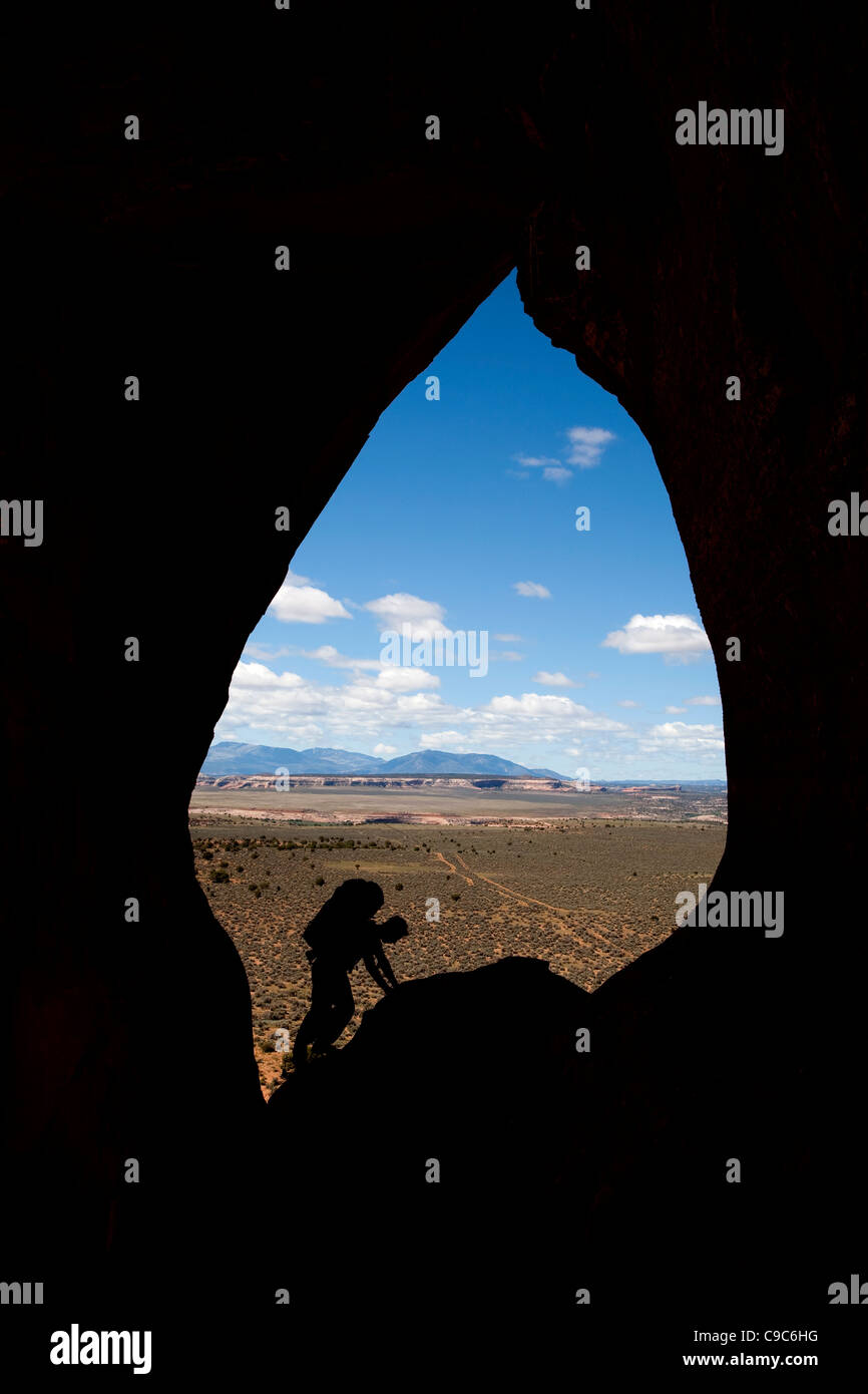 En grimpant à la fenêtre en verre rock arch près de Moab dans l'Utah USA silhouetté contre le désert et montagnes Sanpete Banque D'Images