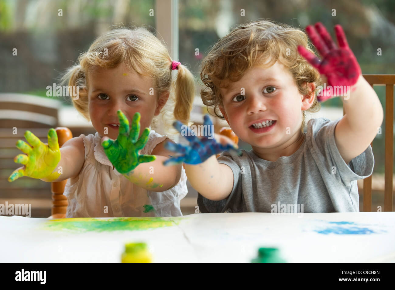Petite fille et garçon montrant les mains couvertes de peinture, portrait Banque D'Images