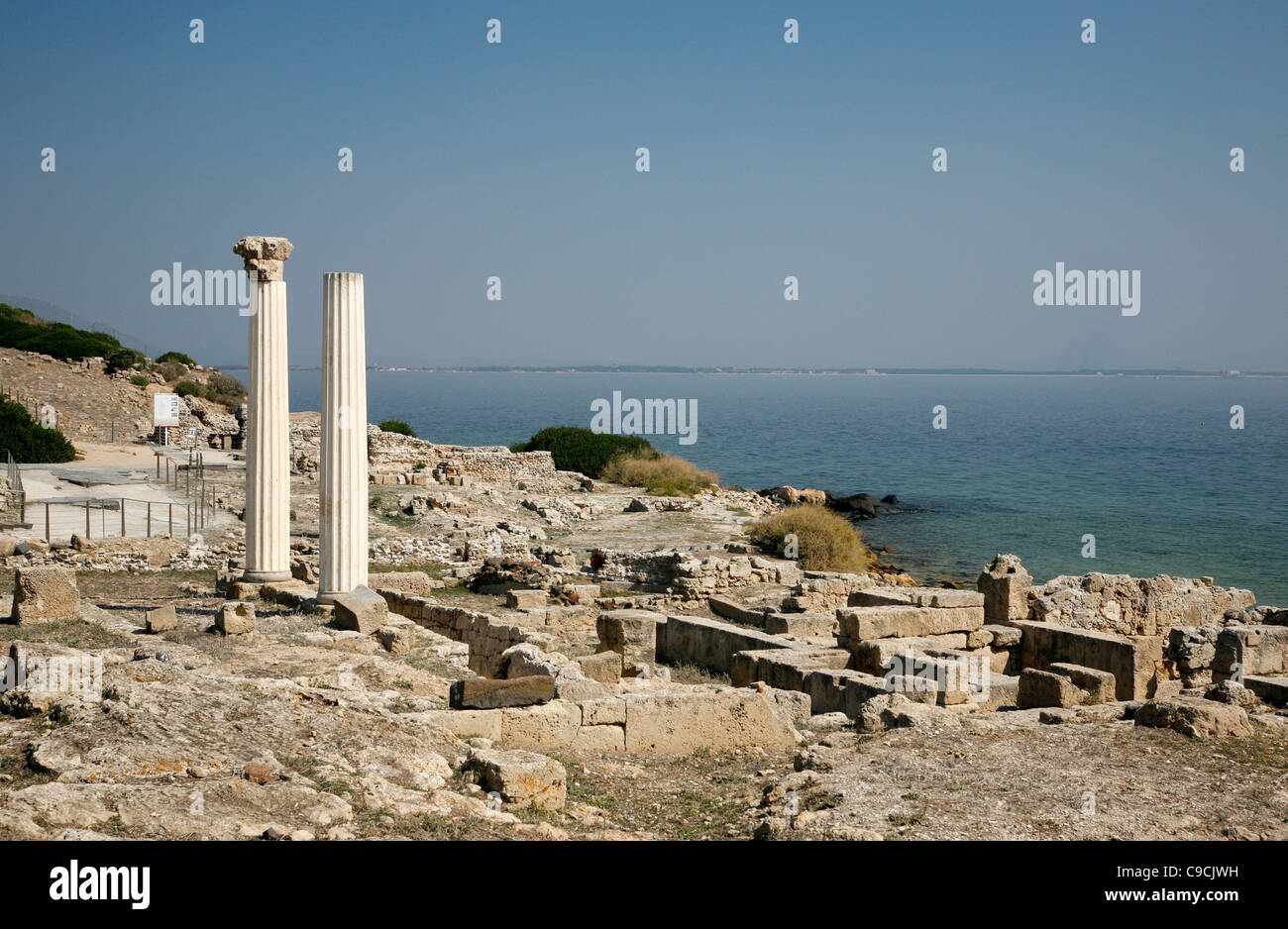 Vue sur les ruines de Tharros et les colonnes de Tempio Tetrastilo, péninsule de Sinis, Sardaigne, Italie. Banque D'Images