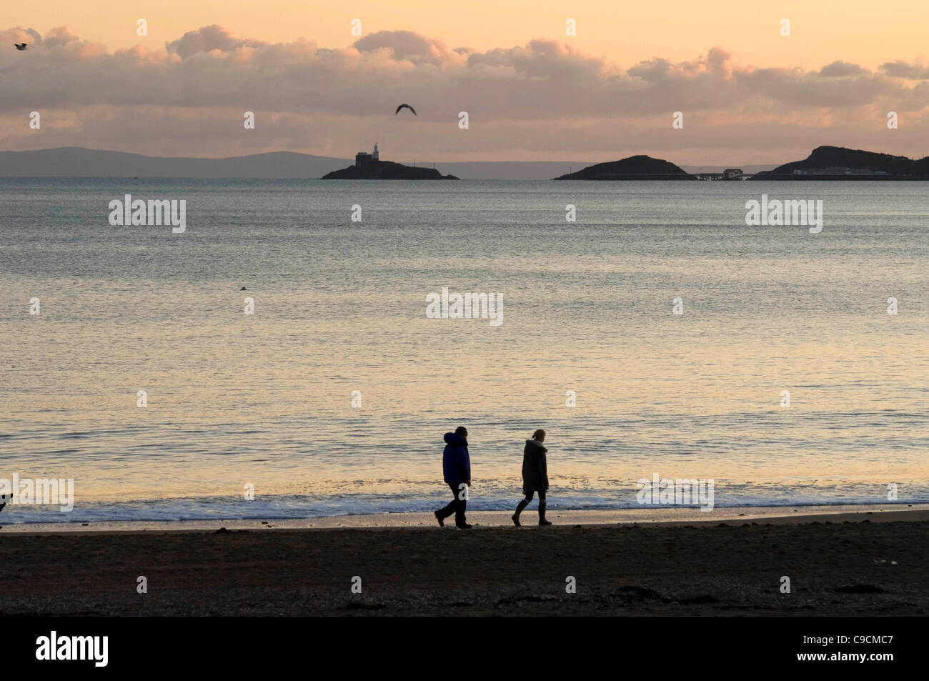 Les randonneurs de découvrir le magnifique coucher de soleil sur la Baie de Swansea, dans le sud du Pays de Galles sur un après-midi d'automne. Banque D'Images