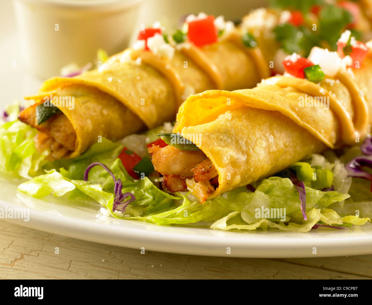 Deux chicken taquitos surmontée avec de la sauce, la sauce et le fromage sur un lit de laitue Banque D'Images