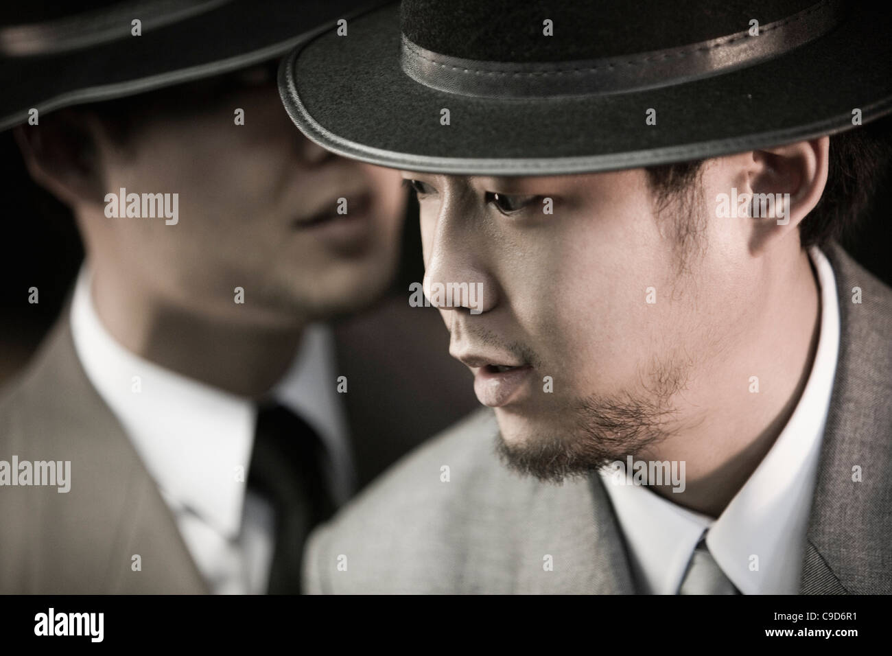 Portrait de deux jeunes hommes asiatiques portant des costumes et chapeaux Banque D'Images