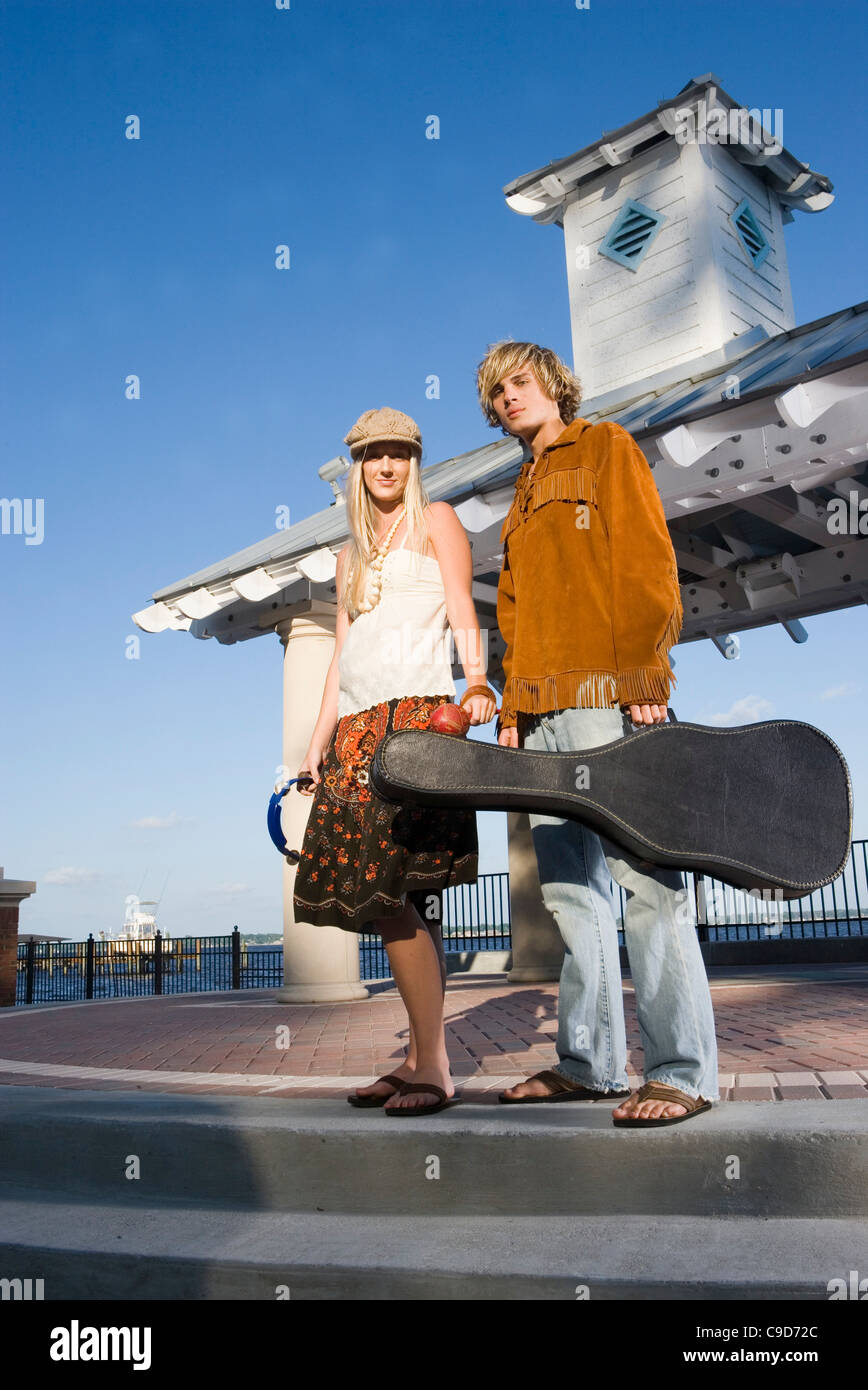 Un jeune couple vintage des années 60, costumes hippie posant avec une guitare et un tambourin Banque D'Images