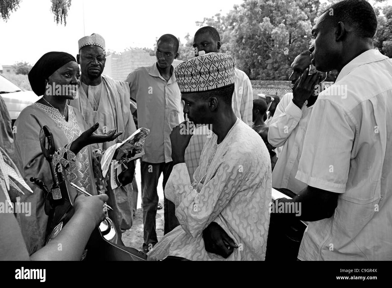 19 septembre 2010 - Kura, Kano, Nigéria - Josephine Kamara, l'agent de l'UNICEF chargé de la mobilisation sociale pour la campagne de vaccination contre la poliomyélite, à gauche en noir, tente de convaincre les dirigeants locaux pour que les enfants vaccinés contre la polio..fanatisme religieux et la désinformation ont forcé les villageois à l'UM Banque D'Images