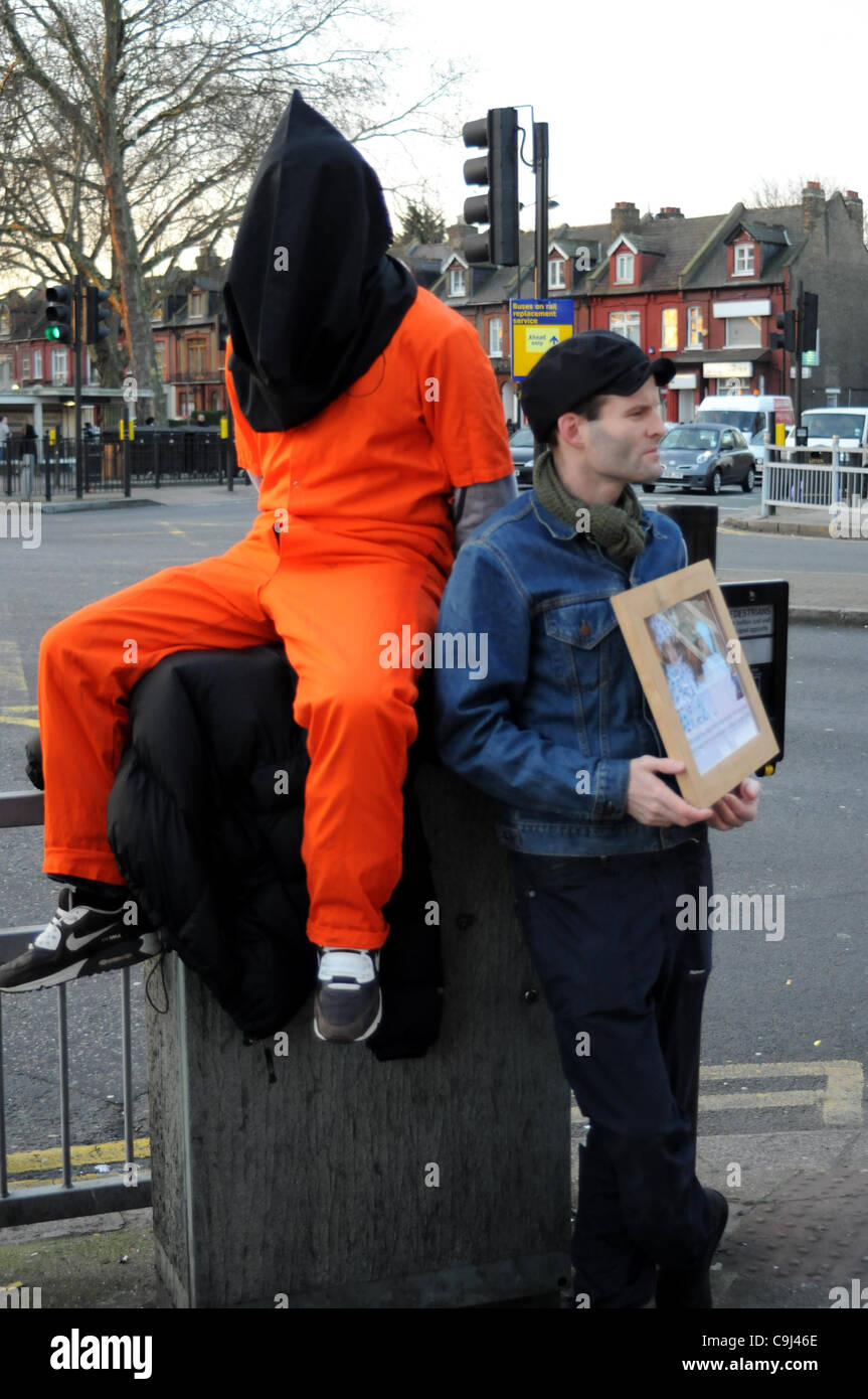 Londres, Royaume-Uni. 11Th Jan, 2012. Un manifestant portant une combinaison de saut à la prison d'orange et noir est assis sur le capot d'une boîte de jonction au cours de la Guantanamo Journée d'action. À 8h00 des manifestants à Turnpike Lane, London, ont été marquant le 10e anniversaire de l'ouverture du camp de prisonniers. Banque D'Images