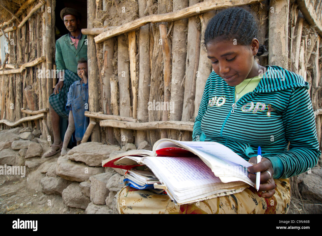 16 janvier 2012 - Farta (woreda, Gondar sud (zone, l'Éthiopie, le 16 janvier 2012, Ayva Niva), l'Ethiopie - un projet pilote de TESFA participant utilise la lumière de fin d'après-midi pour étudier ses leçons d'éducation civique à l'extérieur de la maison de sa famille en Ethiopie, Ayva Niva. Cette jeune femme a pris part dans le groupe de contrôle de la Banque D'Images