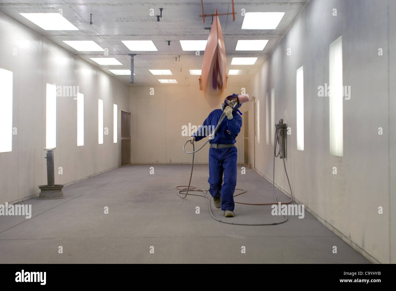 London, Ontario, Canada - le 5 mars 2012. Steve Mann s'applique couches de peinture sur la coque de course unique dans la peinture, à Hudson Boat Works. Banque D'Images