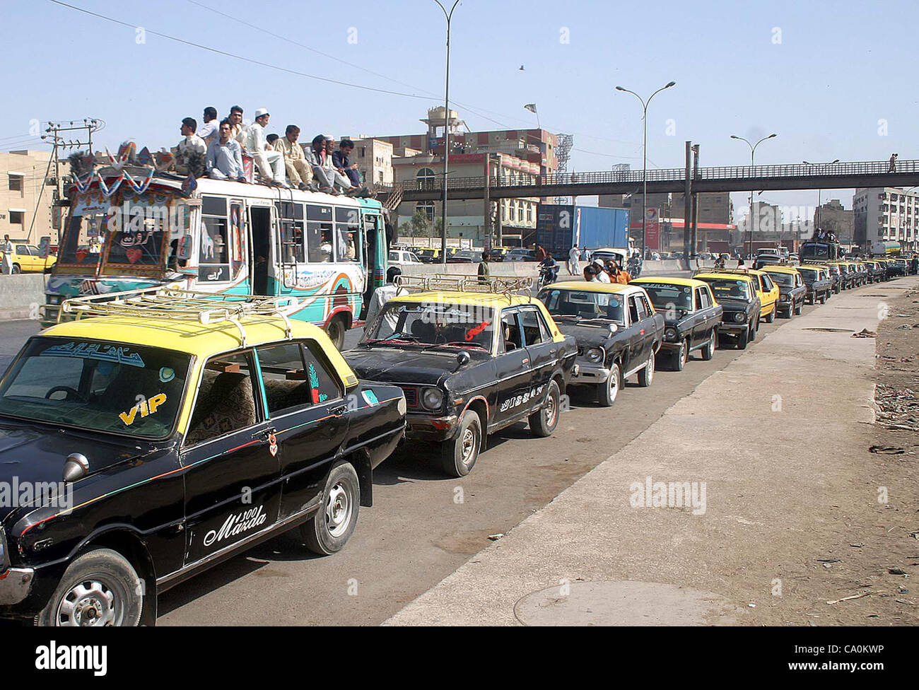 Une longue file de véhicules de passagers (taxi) vu parqué sur une route alors que les gens voyagent sur un autobus de passagers surchargé comme des résidents de ville sont confrontés les non-disponibilité des transports publics en raison de la fermeture d'urgence des stations GNV pour vingt-quatre heures sous l'homme charge GNC Banque D'Images