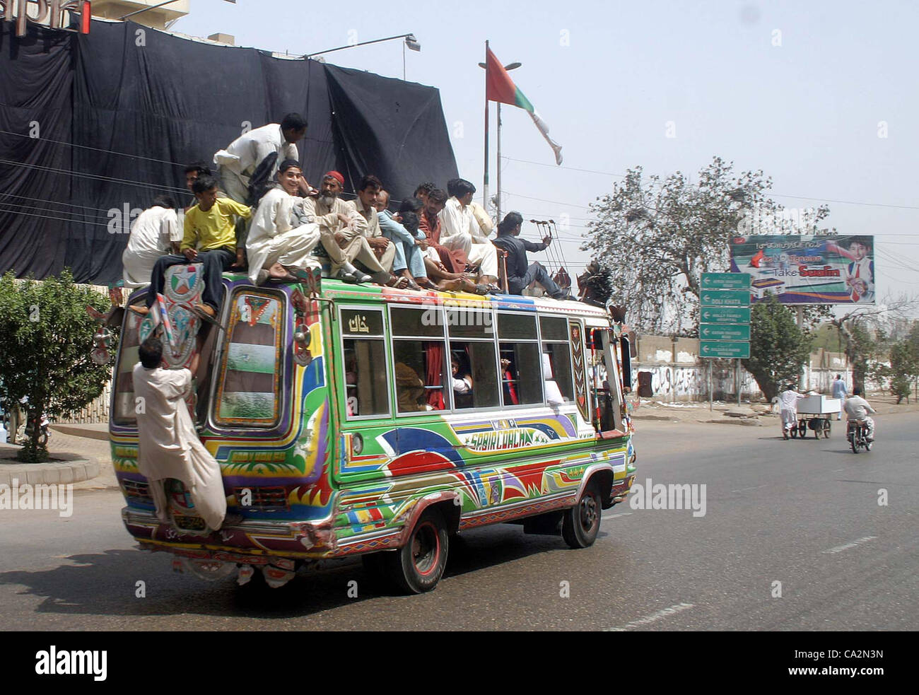 Les gens voyagent sur le toit d'une voiture alors que des habitants de la ville sont confrontés à des problèmes en raison de la non-disponibilité des transports publics au cours de la violence politique en cours à Karachi le Mardi, Mars 27, 2012. Banque D'Images