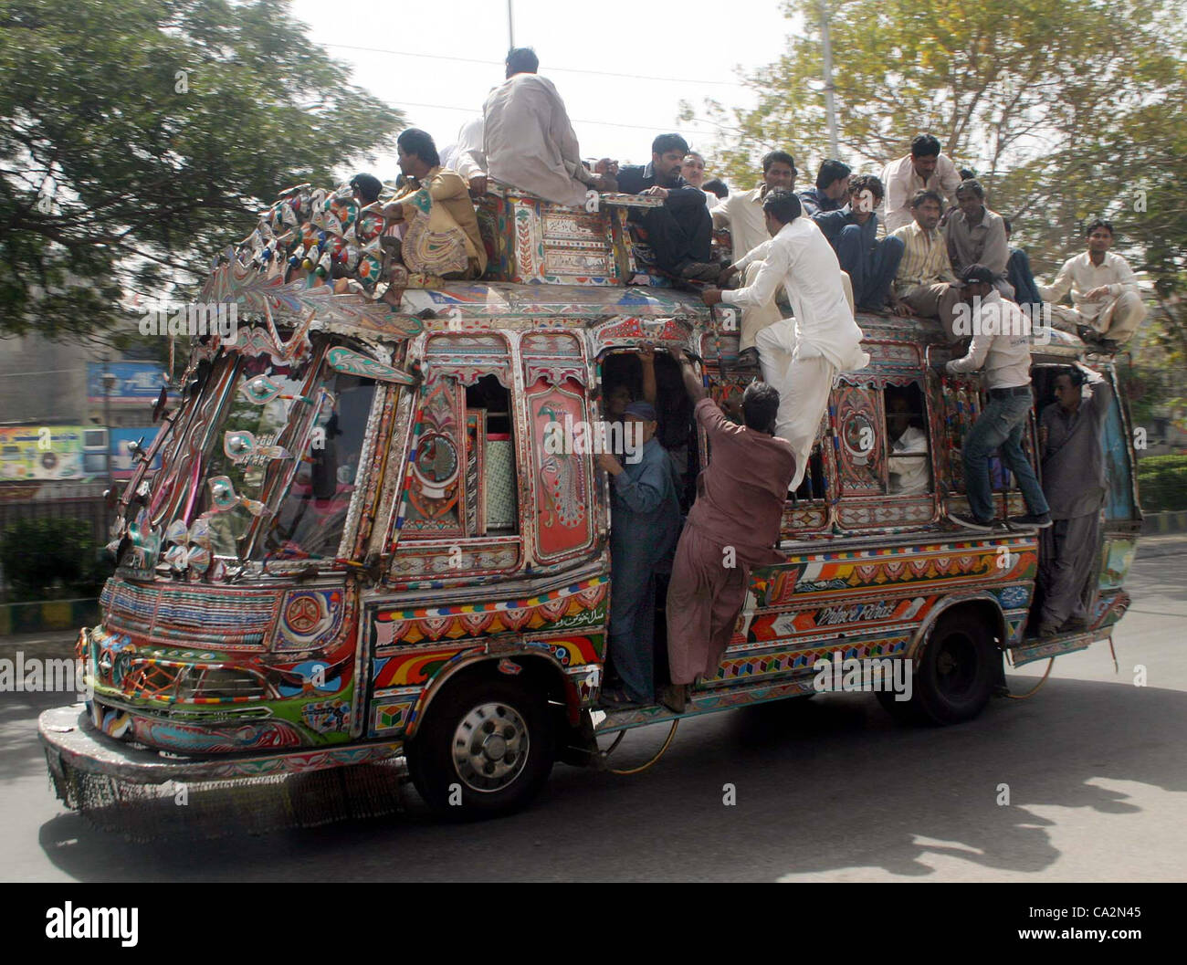 Les gens voyagent sur le toit d'une voiture alors que des habitants de la ville sont confrontés à des problèmes en raison de la non-disponibilité des transports publics au cours de la violence politique en cours à Karachi le Mardi, Mars 27, 2012 Banque D'Images