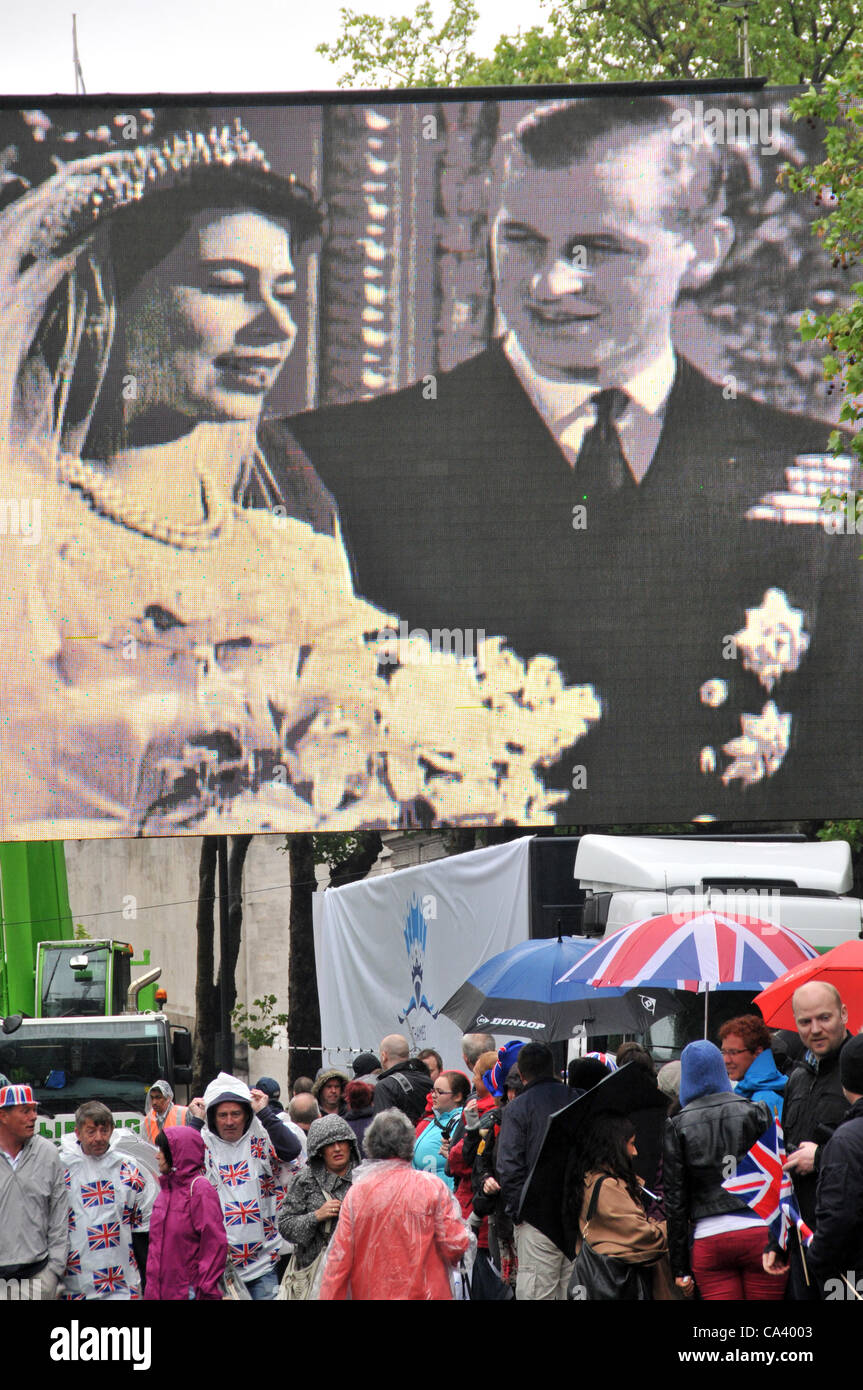3e juin 2012. Victoria Embankment, London, UK. Un grand écran montre le mariage de la Reine Elizabeth et le Prince Phillip comme la foule jusqu'à l'inondation de l'Embankment tôt le matin pour se préparer à voir le spectacle sur la Tamise. Banque D'Images