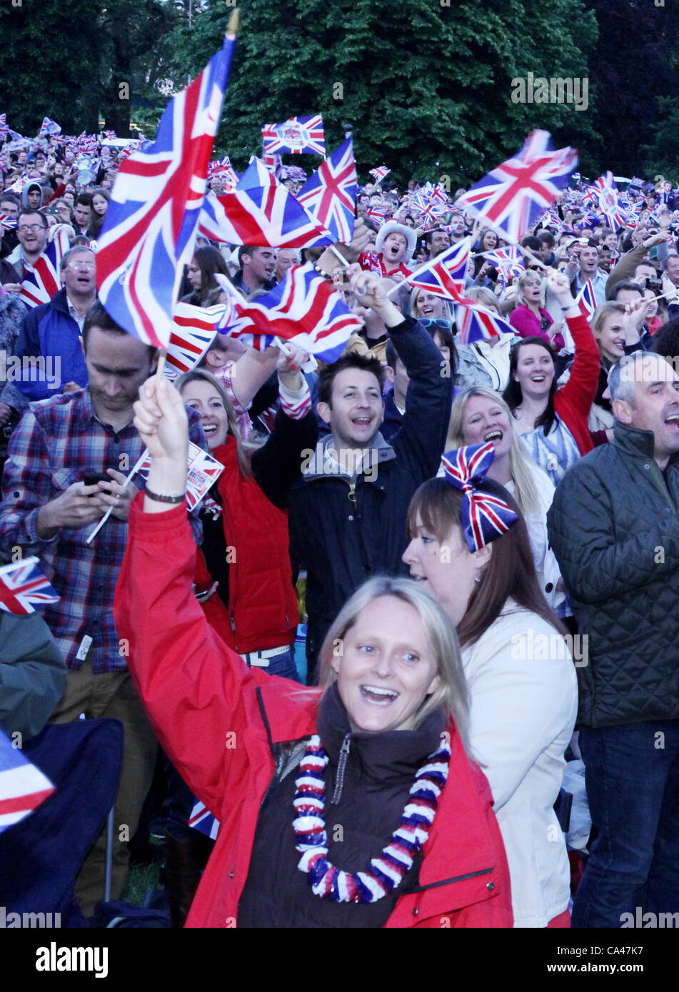 Londres, Royaume-Uni. Le 4 juin 2012. Fans de tous les âges en brandissant des drapeaux qu'ils regarder et apprécier le Concert pour célébrer le Jubilé de diamant de la reine sur les grands écrans à St James's Park. Banque D'Images