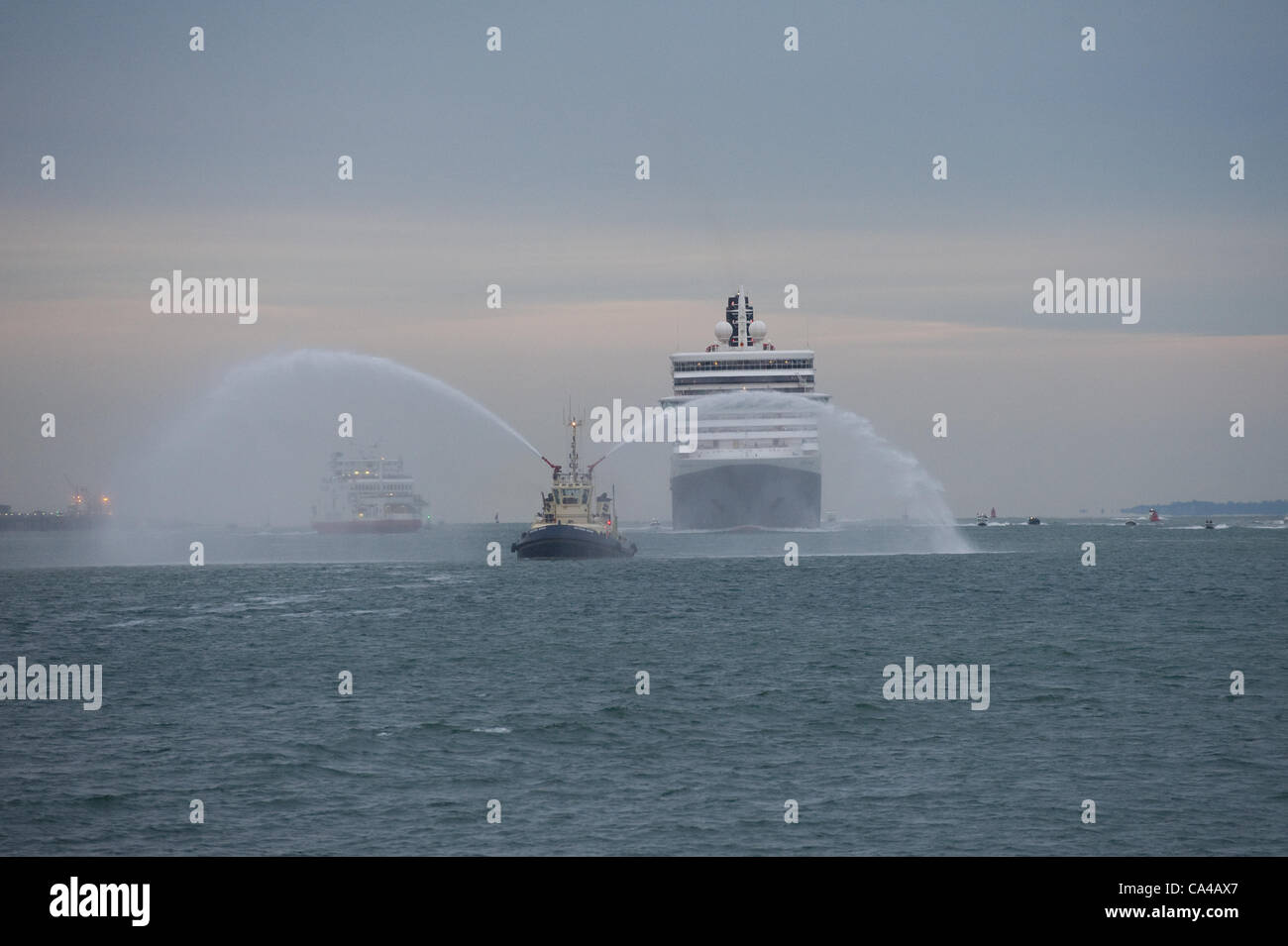 Southampton, UK. Les trois navires de croisière Cunard Queen Elizabeth, Queen Victoria et Queen Mary 2 Arriver à Southampton docks à l'aube pour les célébrations du jubilé de diamant sur le 5e juin 2012. Image représente la reine Victoria avec l'eau du remorqueur salute. Credit : Stefan Venter / Alamy Live News Banque D'Images
