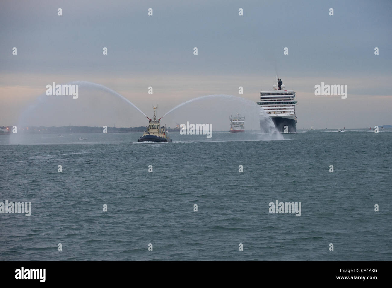 Southampton, UK. Les trois navires de croisière Cunard Queen Elizabeth, Queen Victoria et Queen Mary 2 Arriver à Southampton docks à l'aube pour les célébrations du jubilé de diamant sur le 5e juin 2012. . Image représente la reine Victoria avec l'eau du remorqueur de port salut entrer Crédit : Stefan Venter / Alamy Live News Banque D'Images