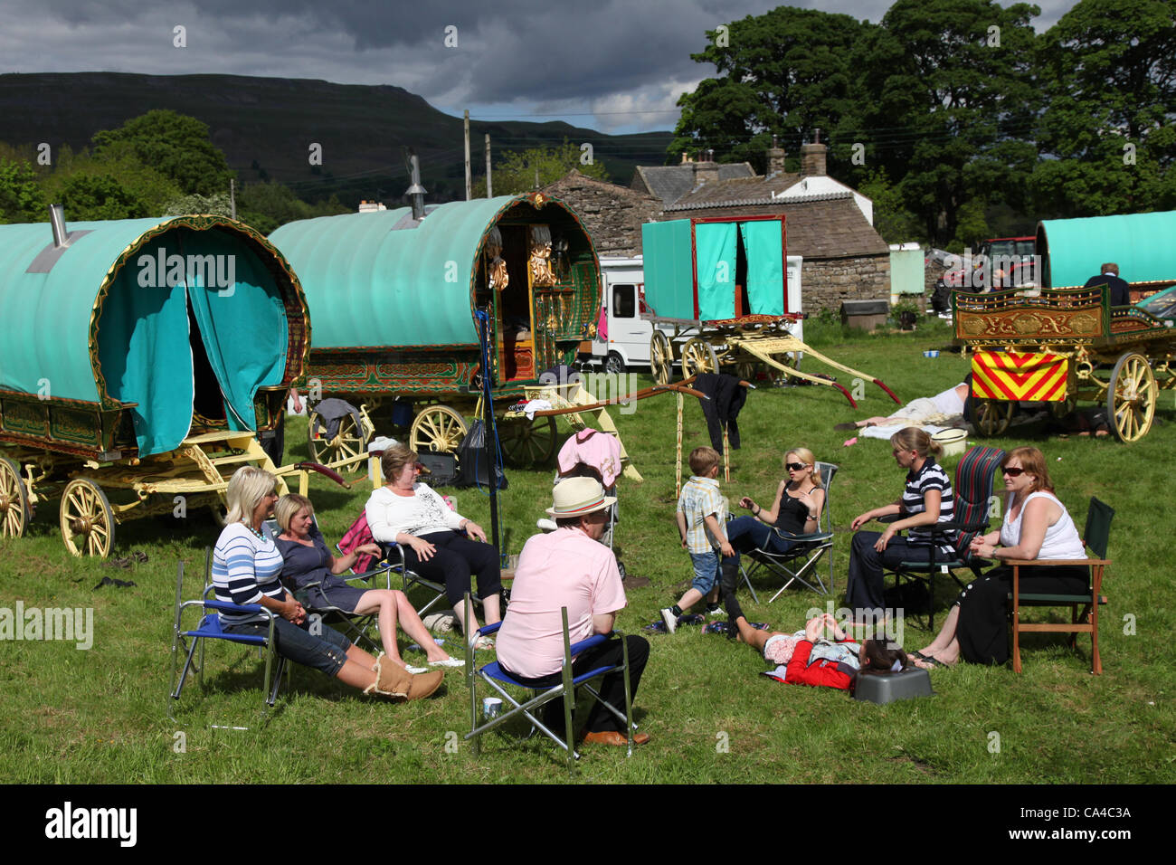 Caravanes de voyageurs tziganes ; feu de camp familial avec des caravanes tziganes traditionnelles de la Caravan de Vardo ou des chariots couverts de toile « Bow Top » en route vers le rassemblement annuel à Appleby, South Lakeland , UK CoB and Romany showman hébergement Wagon of the Traveling Community, camping à Bainbridge, dans les Dales du Yorkshire du Nord,En route vers la foire hippique Appleby, Royaume-Uni Banque D'Images