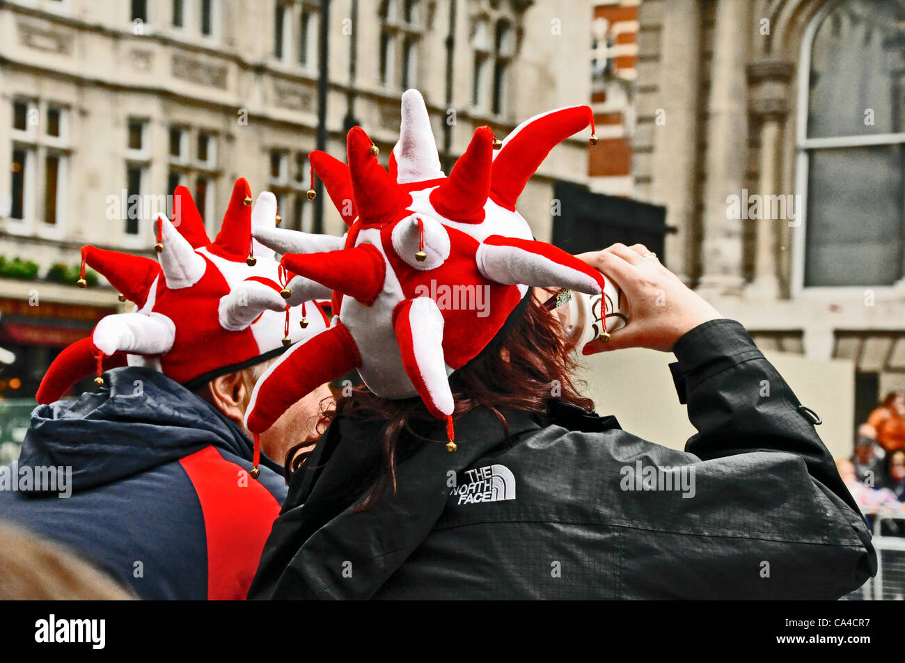 Queens - Jubilé de diamant sur curieux en rouge et blanc chapeau jesters, attendre l'imprimeur de la procession en Whitehall Banque D'Images