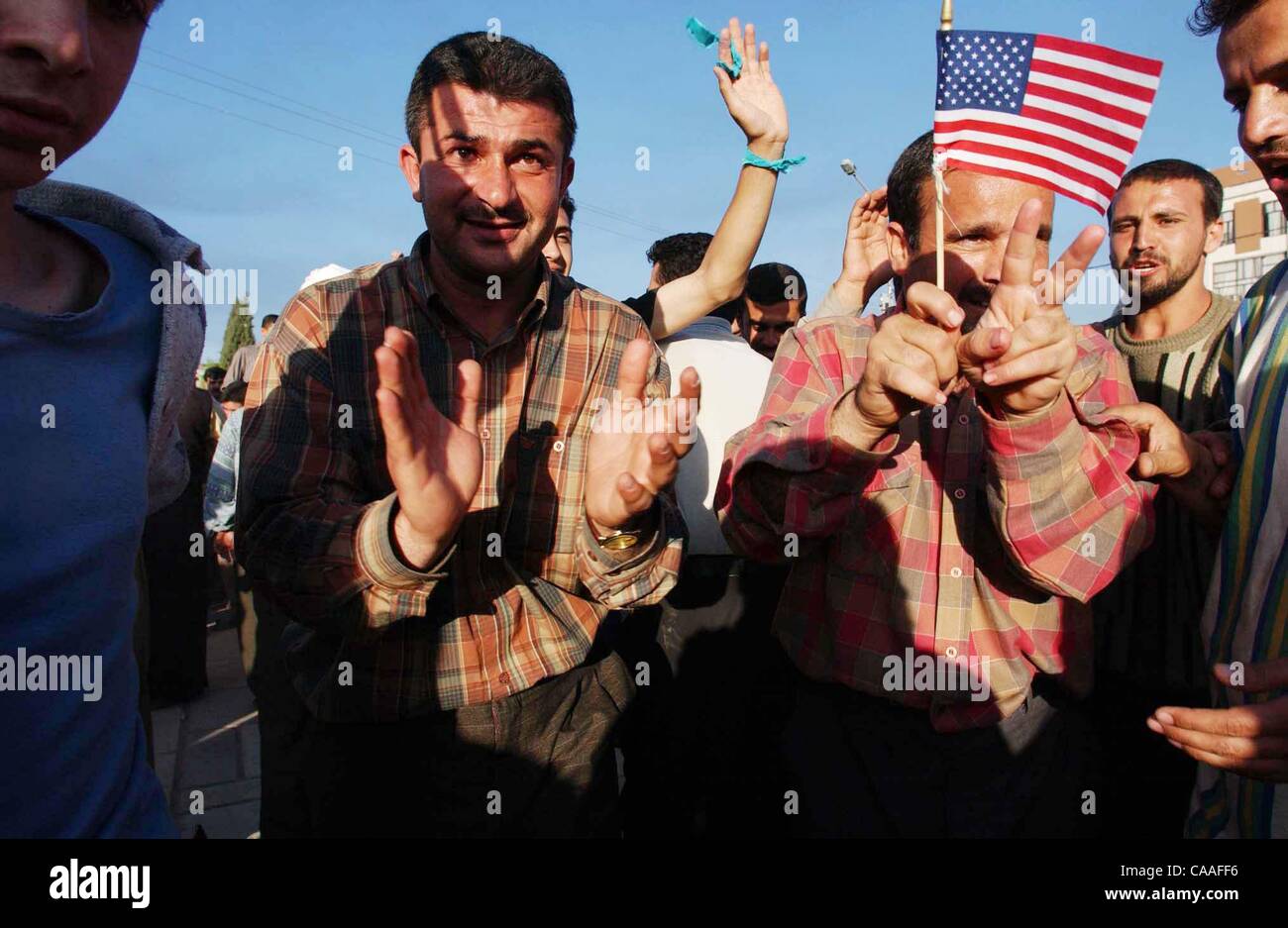 (Publié le 04/13/2003, A-12) : NC KIRKOUK x010 .......... Le 10 avril 2003, Kirkouk, Irak ......brandissant le drapeau américain Kurdishmen de Kirkouk la danse dans les rues après l'heure ils ont détruit une statue de 25 pieds de hauteur du Président Saddam Hussein. Les hommes et les femmes dans les rues inondées après les forces de coalition cla Banque D'Images