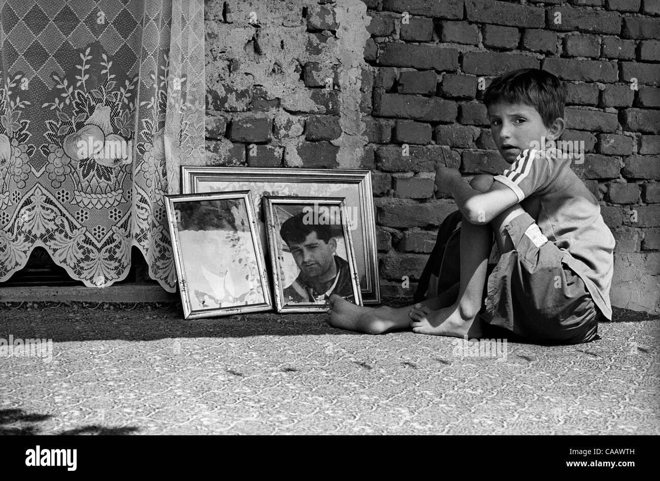 Un garçon est assis à côté de son père manquant photo à Velika Krusa/Krusha  e Mahde, au Kosovo. Plus de 50 de ses hommes ont été tués et brûlés par les  forces