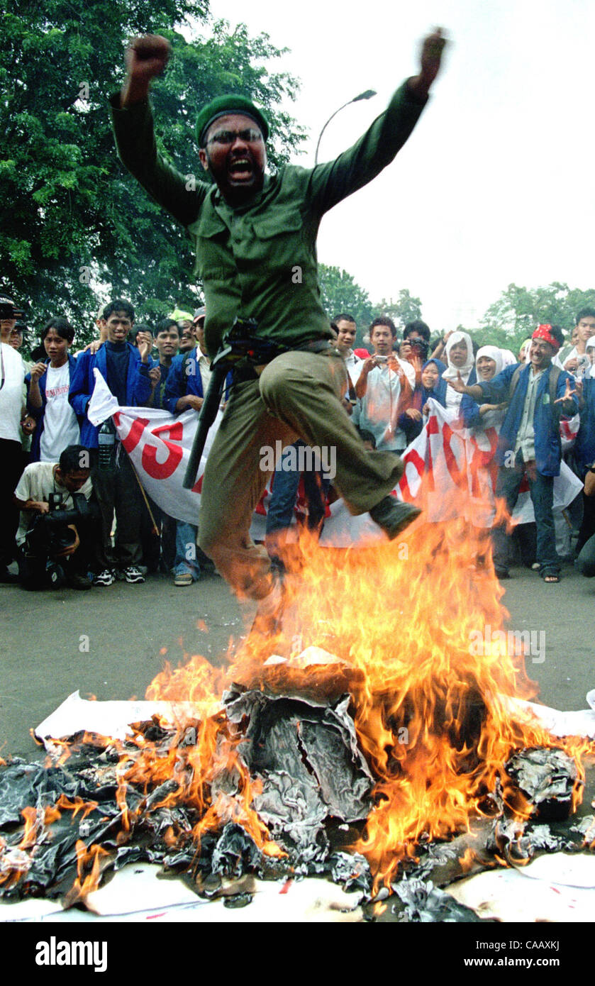 JAKARTA, INDONÉSIE - 28 mars 2003 une étudiante musulmane indonésienne saute au-dessus du drapeau américain et brûlé une effigie du Président Bush au cours de la démonstration s'opposer à l'invasion de l'Iraq en dehors de USA Ambassade des États-Unis à Jakarta, le 28 mars 2003. Les musulmans en Indonésie, le pays le plus peuplé de la nation islamique , wa Banque D'Images