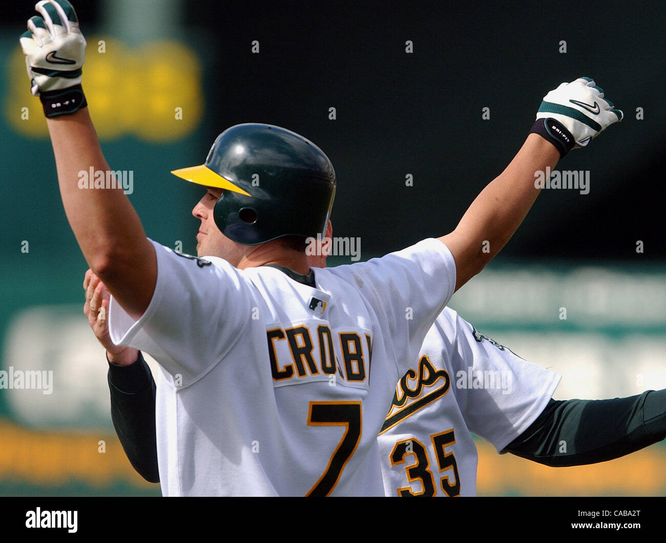 Oakland Athletics Bobby Crosby, # 7, célèbre entraîneur de première avec Brad Fischer, # 35, après avoir atteint la première base sur un infield seul qui a permis à son coéquipier Jermaine Dye, # 24, pour marquer le point gagnant contre les Royals de Kansas City dans la 11e manche de leur jeu Samedi, 22 mai 2004 au Banque D'Images