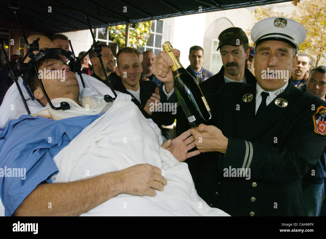 Brian Smith, 43 pompiers, d'échelle à l'entreprise 44, reçoit une bouteille de Champagne Moet de bain Co. 44 capt Steven Luisi comme il est libéré de nouveau York-Presbyterian Weill Cornell Medical Center sur East 68th Street. Smith est tombé 30 pieds à partir d'un godet de l'échelle pendant la lutte contre l'incendie dans le Bronx 22 da Banque D'Images