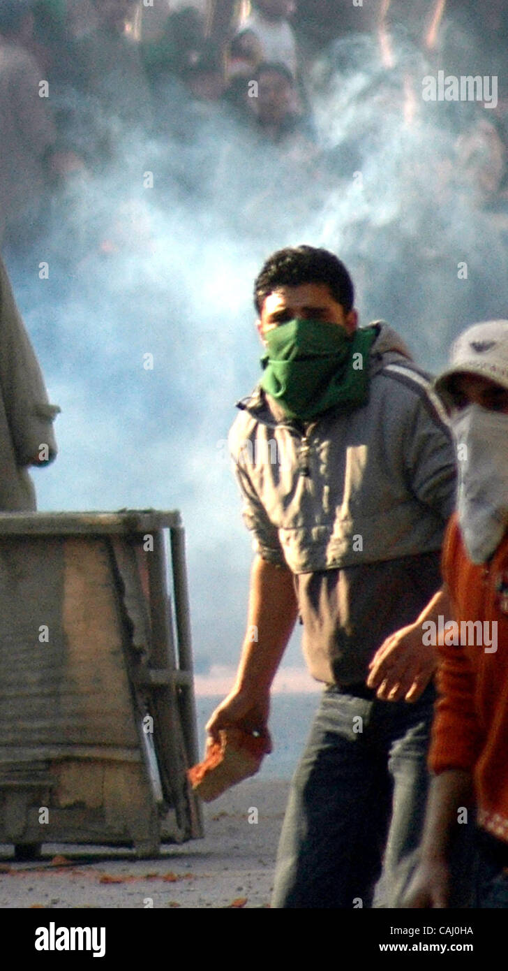 Un manifestant lance des pierres en direction du Cachemire indien les policiers au cours d'une manifestation à Srinagar, la capitale d'été du Cachemire indien, le jour suivant l'assassinat de l'opposition pakistanaise, Mme Benazir Bhutto, le 28 décembre 2007. La police au Cachemire sous contrôle indien se sont affrontés vendredi avec hundr Banque D'Images