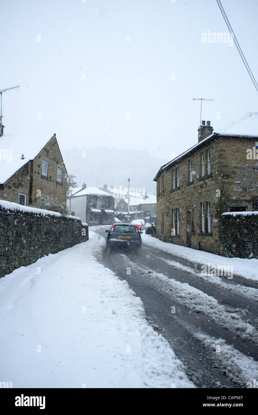 Luttes voiture sur la neige couverts les routes dans l'historique village de Peak District, Derbyshire, Royaume-Uni Eyam le mercredi 4 avril 2012. Le Met Office a émis des avertissements météo pour une grande partie du nord de la France. Banque D'Images