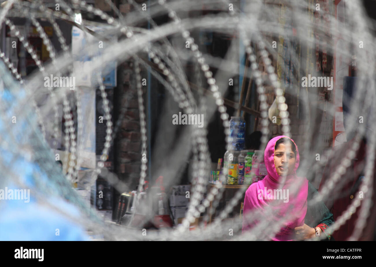 Une fille musulmane du cachemire à pied près de barbelé comme paramilitaires indiennes trooper dépose le bunker à Srinagar, la capitale d'été du Cachemire indien. 20, avril, 2012. Le bunker a été construit quelques 22 ans en arrière lorsque l'anti-insurrectionnelles de l'Inde a éclaté dans la région. Processus de suppression d'bunke sécurité Banque D'Images