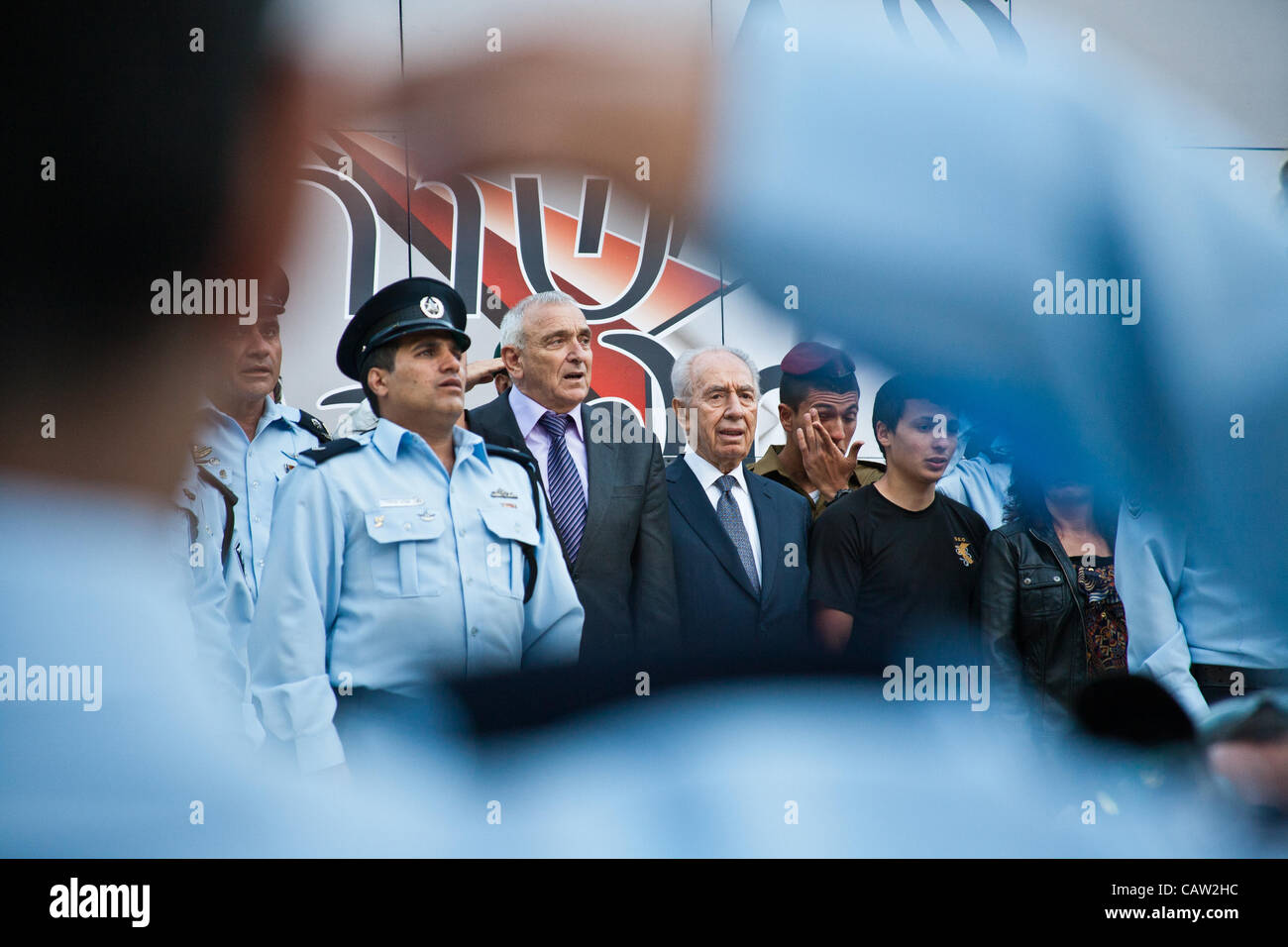 Le Président Shimon Peres et le ministre de la sécurité intérieure Yitzhak Aharonovitch chantent "HaTikva", l'hymne national israélien, la conclusion d'une cérémonie, vue à travers le bras raccourci d'un salut militaire Israël agent de police. Jérusalem, Israël. 23-Apr-2012. Banque D'Images