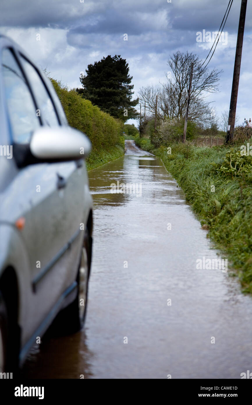 Fortes pluies à l'origine des inondations dans la région de North Norfolk, UK le jeudi 26 avril 2012.Une voiture passe par les eaux des crues sur un chemin de campagne. Banque D'Images