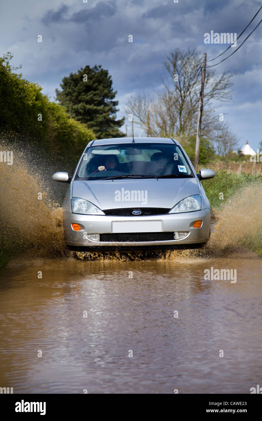 Fortes pluies à l'origine des inondations dans la région de North Norfolk, UK le jeudi 26 avril 2012. Une voiture passe par les eaux des crues sur un chemin de campagne. Banque D'Images