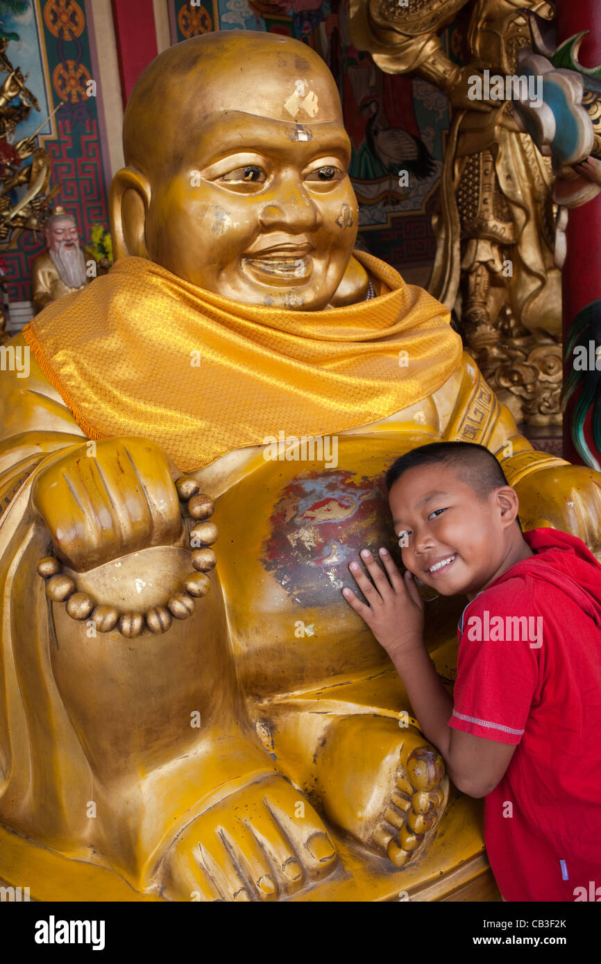 Thaïlande, Bangkok, Chinatown, jeune garçon à Buddha statue Banque D'Images