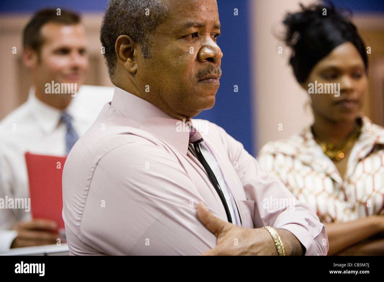 Homme d'âge mûr avec des collègues plus jeunes en arrière-plan Banque D'Images