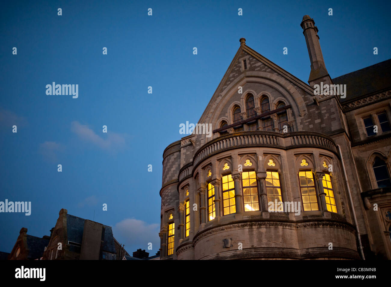 À travers les fenêtres briller les lumières de l'Université d'Aberystwyth architecture gothique 'Vieux College' la nuit, extérieur, Pays de Galles UK Banque D'Images