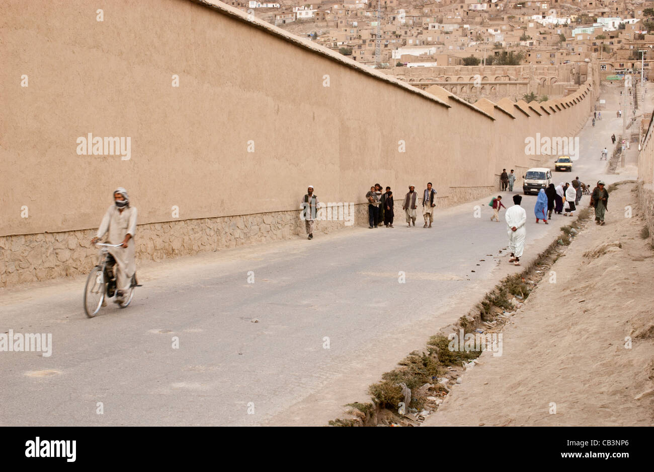 Les gens marcher dans une route qui longe le mur de la Bagh Babur gardens à Kaboul, Afghanistan Banque D'Images