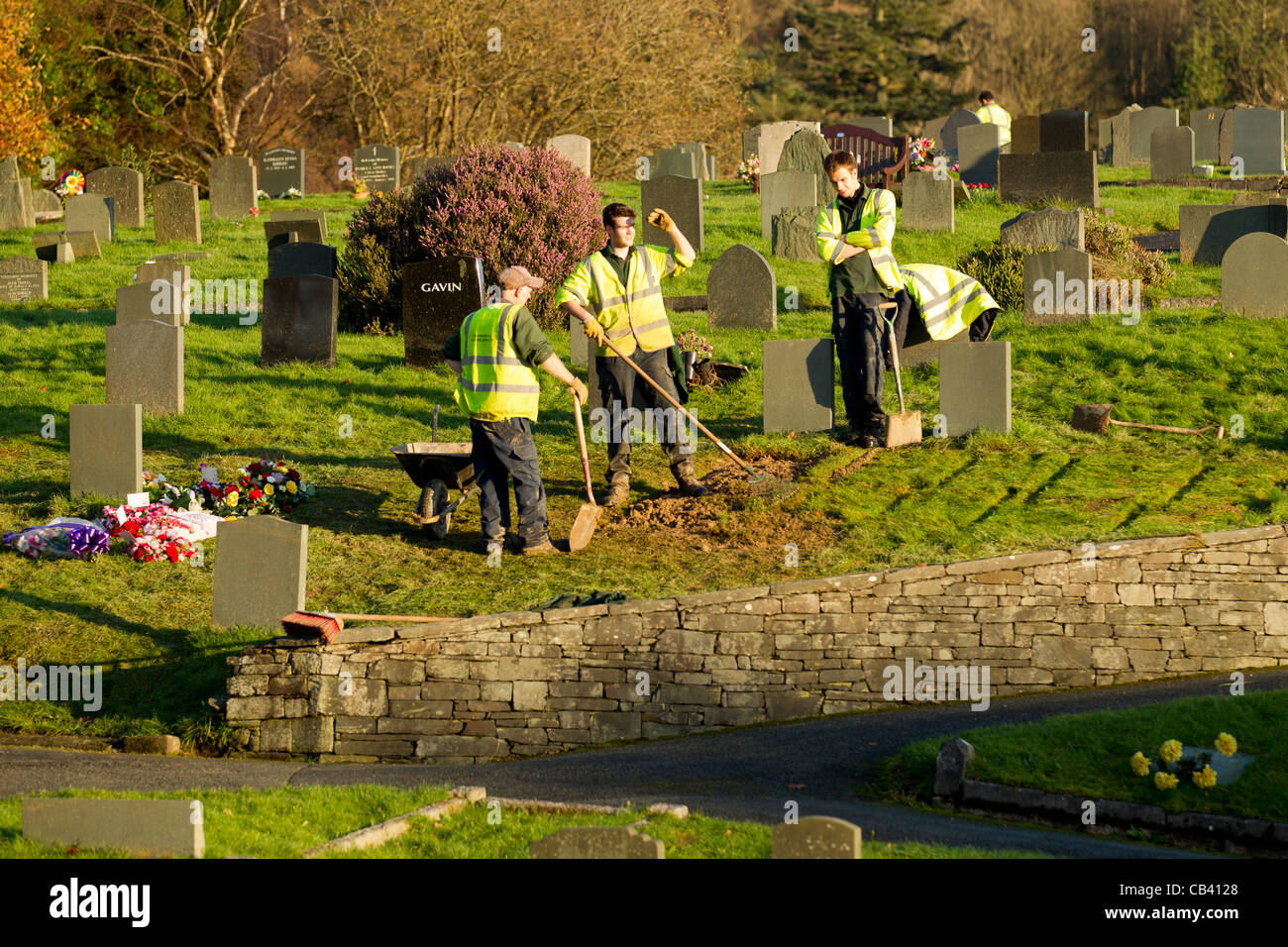 Fossoyeurs en grave yard ranger une grave après l'inhumation dans un cimetière Banque D'Images