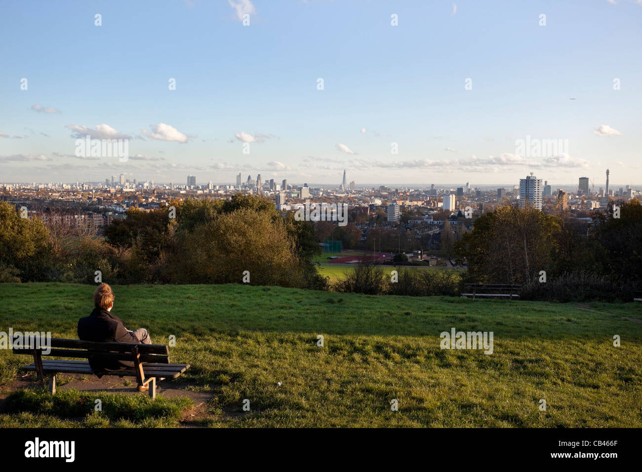 Un homme assis sur un banc en contemplant une vue de la ville de Londres à partir de la colline du Parlement, Hampstead Heath, Londres, Angleterre, Royaume-Uni, Banque D'Images