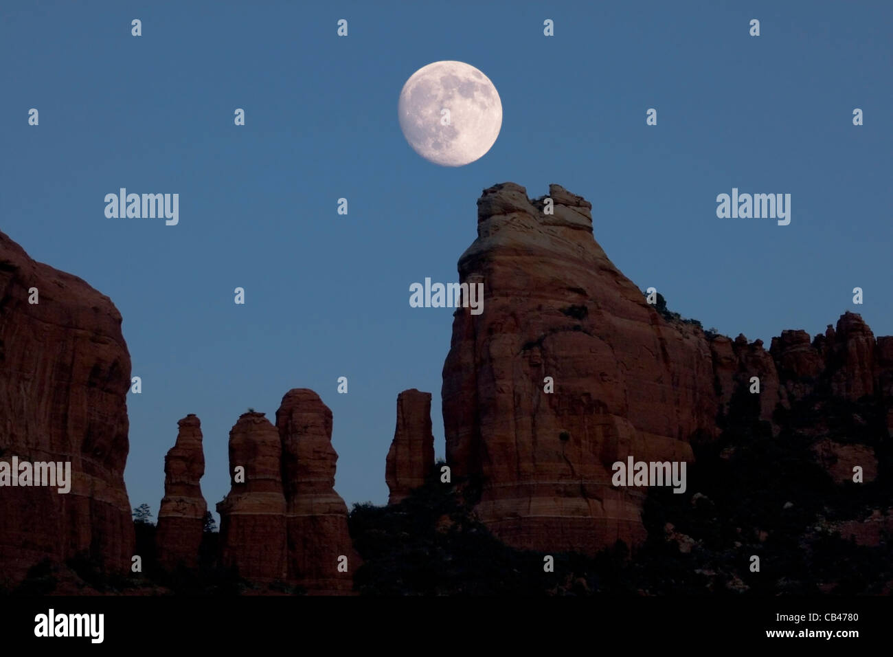 Une presque pleine lune se lève au-dessus de red rock spires près de Sedona, Arizona Banque D'Images