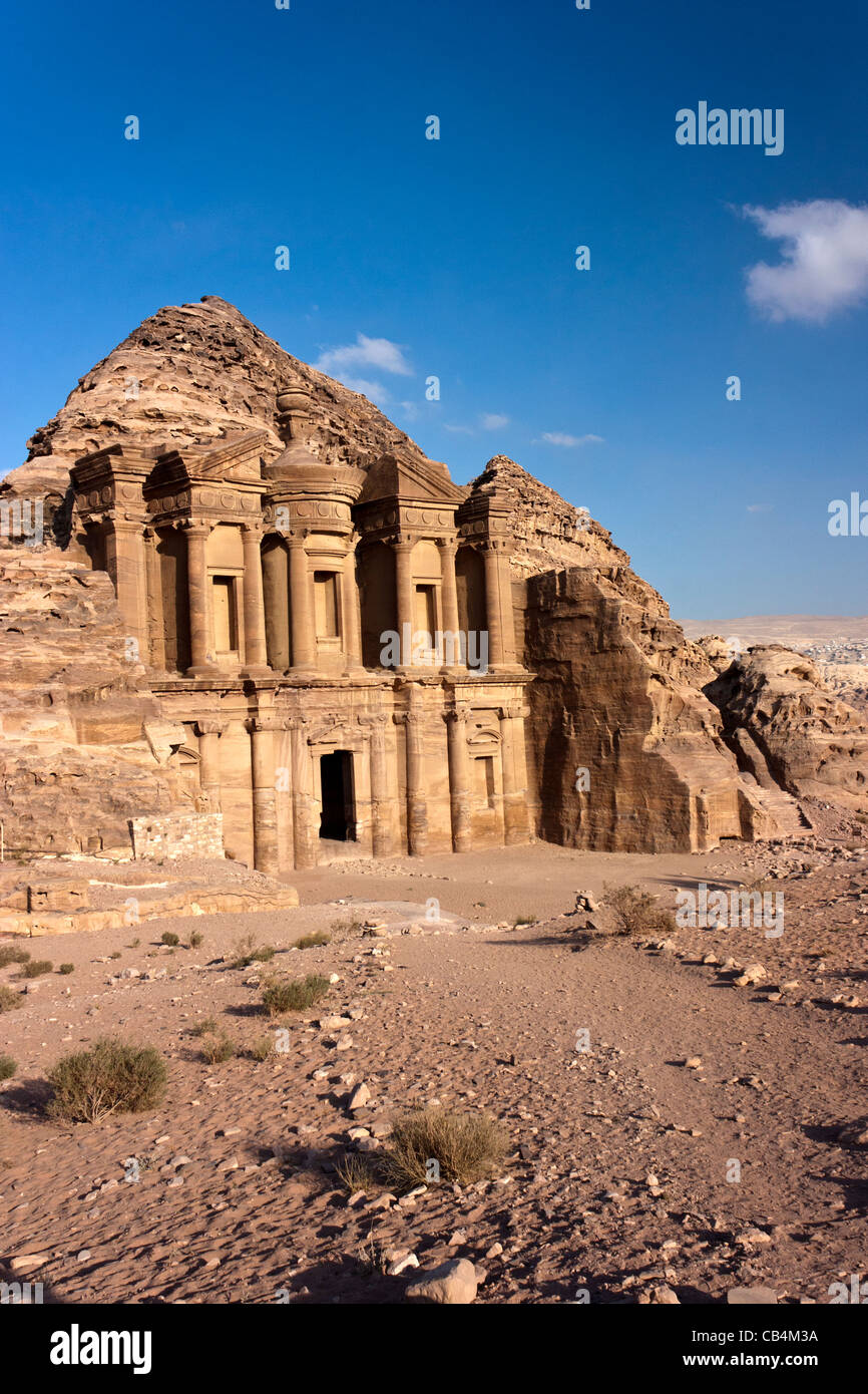 Le monastère (Deir) coupées en les falaises de grès à Petra avec du sable et de touffes d'herbe au premier plan Banque D'Images