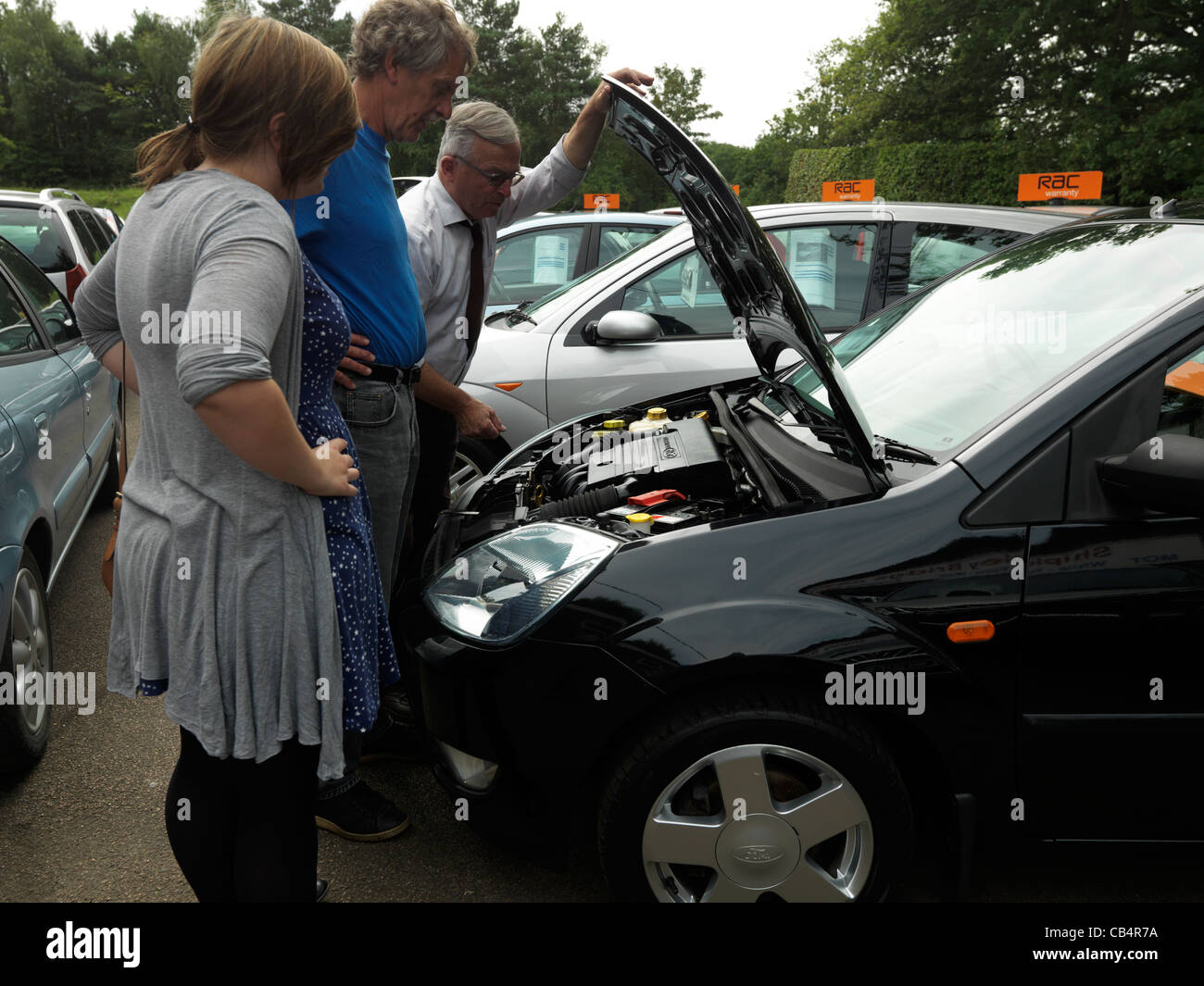 Adolescente avec son père et un vendeur d'automobiles à moteur à l'achat de Ford Fiesta adolescent sa première voiture Banque D'Images