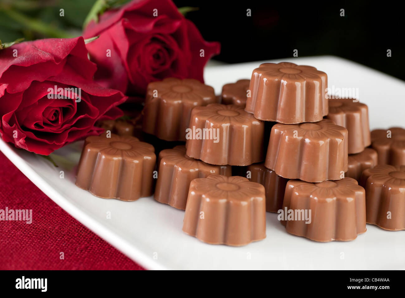Cadeau romantique de roses rouges et de chocolat au lait. Banque D'Images
