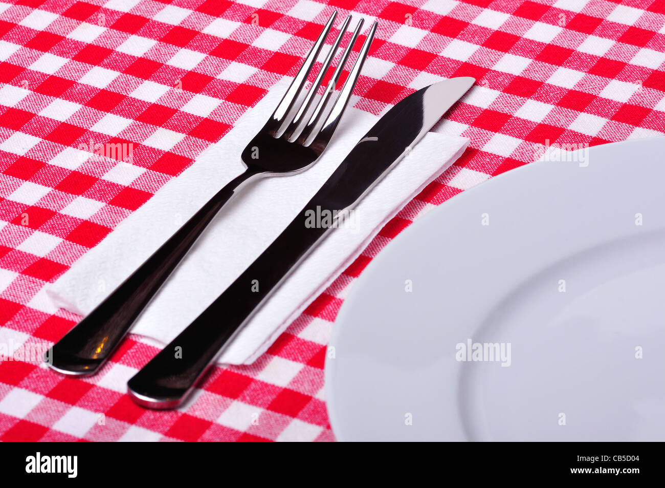 Couteau, fourchette et la plaque sur une table avec une nappe blanche et rouge. Banque D'Images