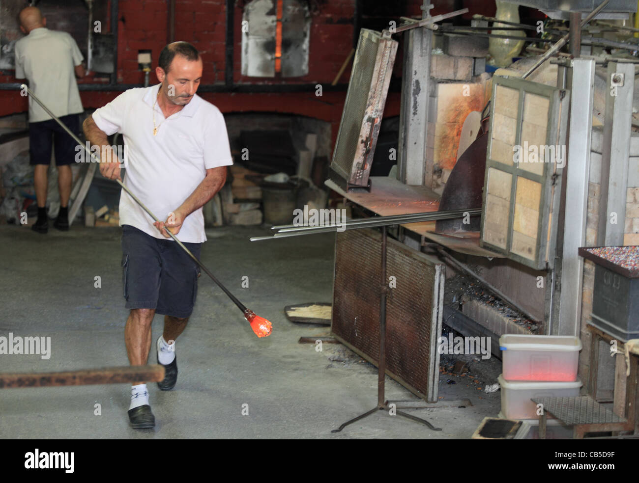 Un artisan dans une usine de Murano travaille sur la production d'un morceau de verre décoratif Banque D'Images